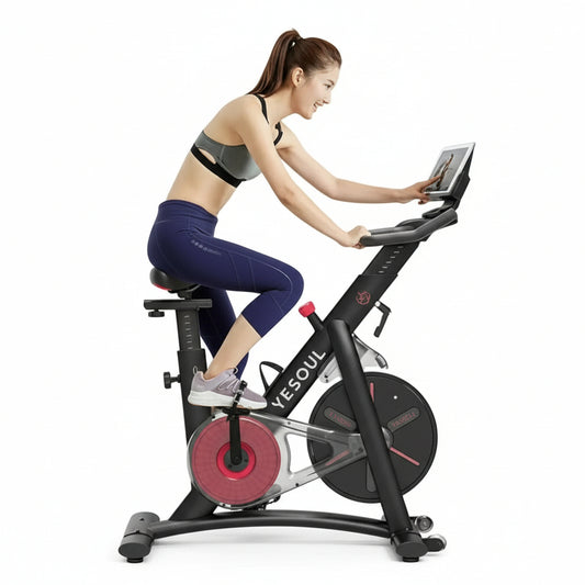 Woman training on a black indoor stationary exercise bike in a bright home setting