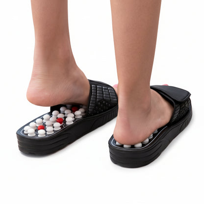 Close-up of Flexora massage slipper pressing acupressure nodes under the toes on a wooden floor