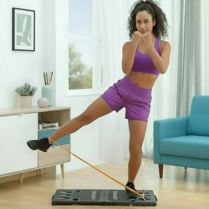 Woman performing side leg raise on Flexora Gympak Max platform with orange resistance band in a living room